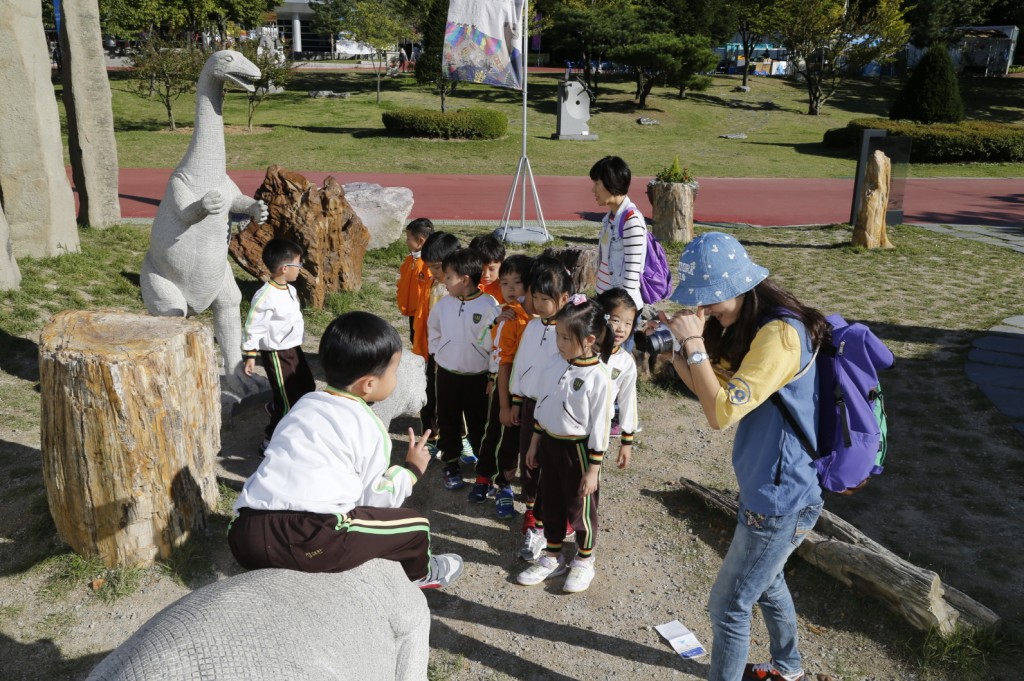 쥬라기로드 앞 공룡모형을 타고 사진을 찍고 있는 어린이들