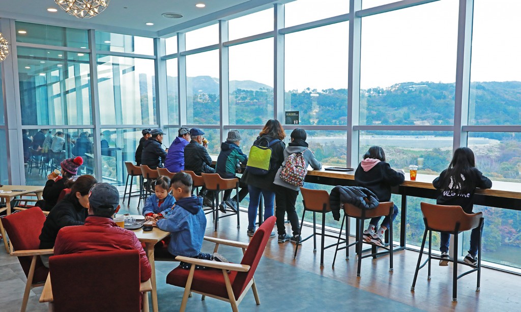 경주타워 전망층 아래 카페선덕에서 경주타와워 보문단지의 전경을 감상하며 차를 마시는 관람객들